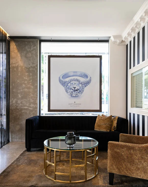 Inside the Culet showroom — a large framed diamond ring portrait above a velvet sofa and brass-and-glass coffee table