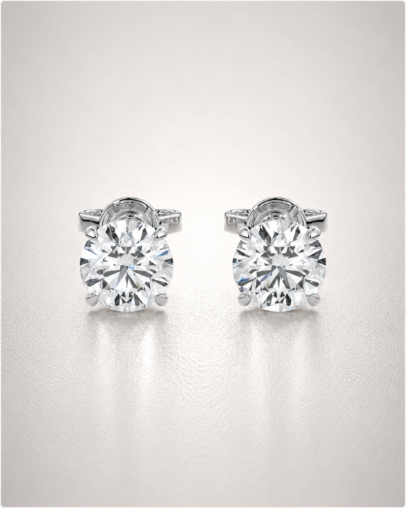 A pair of round-brilliant diamond solitaire stud earrings in four-claw white-gold settings