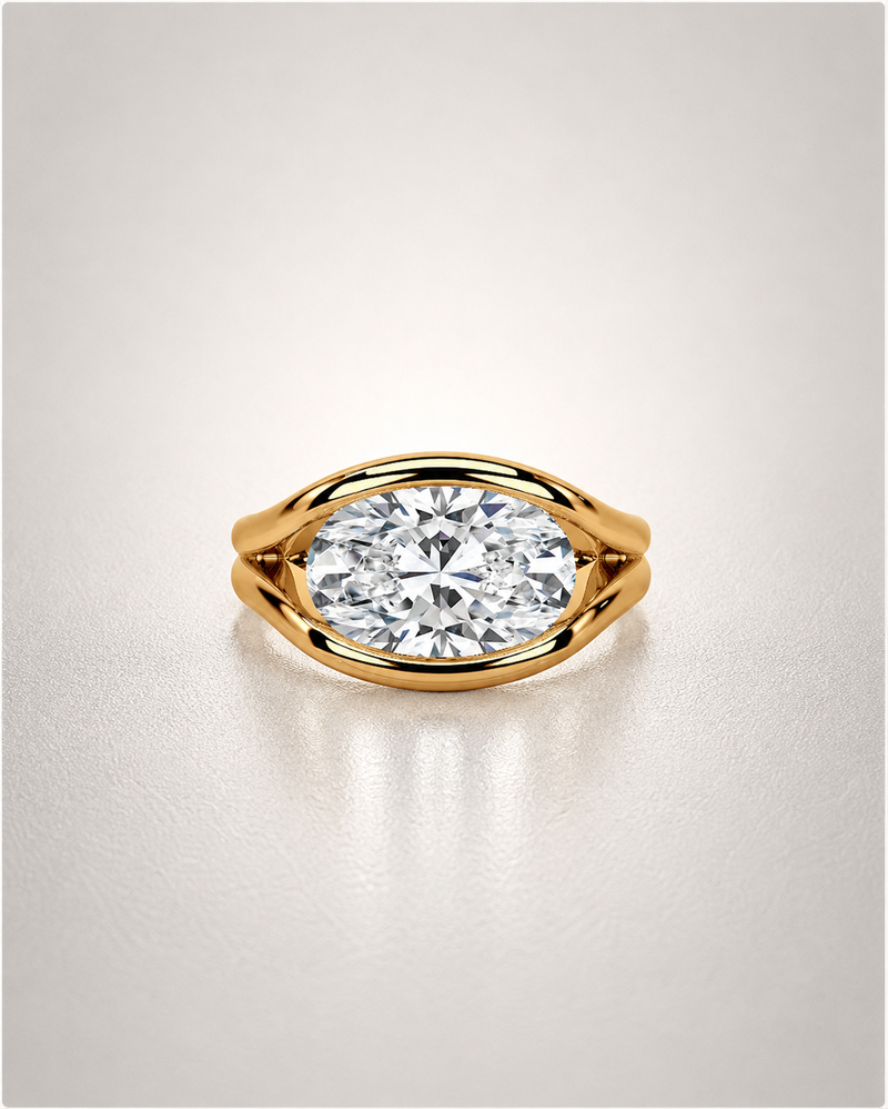 A bold east-west oval-cut diamond ring set horizontally in a sculpted yellow-gold bezel